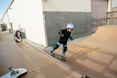 Mother watches and smiles while young son rides half pipe