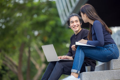 Young woman using mobile phone while sitting outdoors