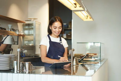 Portrait of young woman standing in kitchen