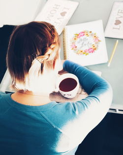 High angle view of woman holding coffee cup on table