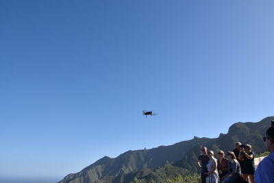 People at airplane against clear blue sky