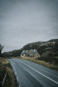 Empty road by mountain against sky