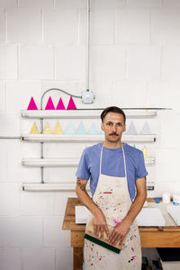 Portrait of smiling young man standing against wall