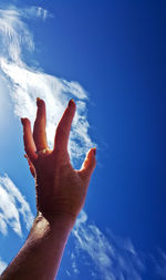 Low angle view of man hand against blue sky