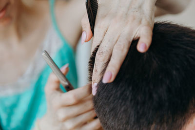 Woman hairdresser cuts hair for male client at home.