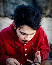 Young man using mobile phone while sitting outdoors