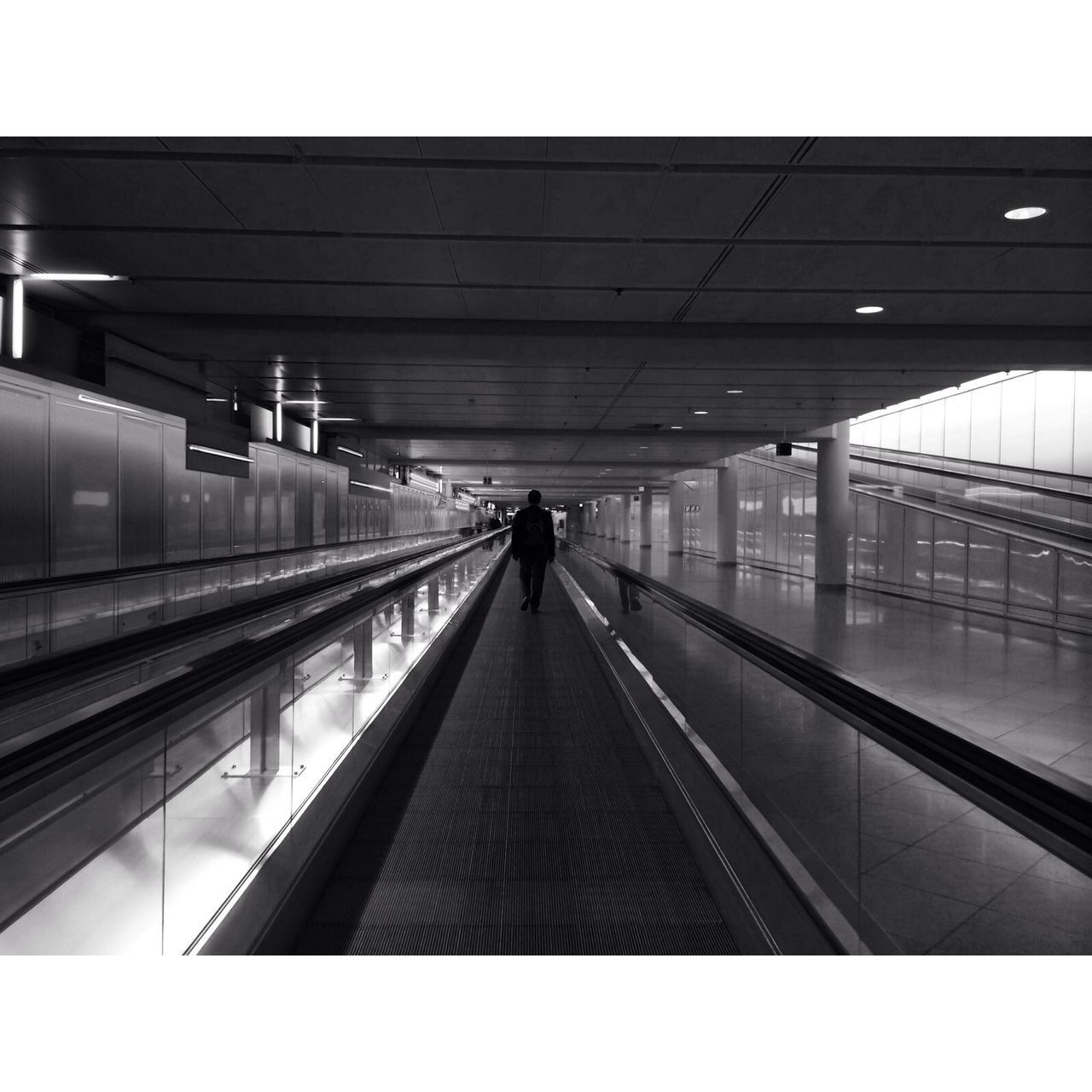 indoors, architecture, built structure, railroad station, railroad station platform, men, walking, railroad track, ceiling, transportation, diminishing perspective, the way forward, lifestyles, rail transportation, rear view, public transportation, person, full length