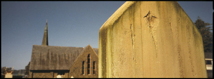 Wooden post in front of building against sky