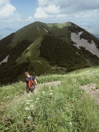 Rear view of man standing on green mountain