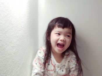 Portrait of cute girl smiling against wall