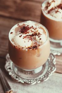 Lattee macchiato coffe drink in glass with cream on wooden table. vitage style.