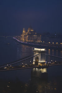 Illuminated chain bridge over river at night