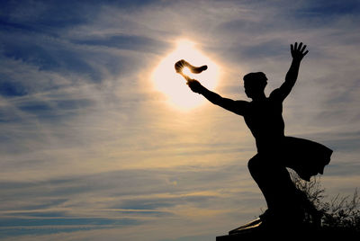 Low angle view of silhouette man standing against sky during sunset