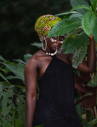 African woman standing in the jungle with tribe marks on her face and african colors as headdress