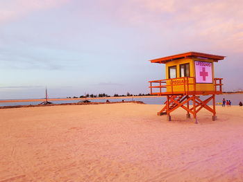 Lifeguard hut at beach against sky during sunset