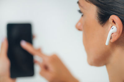 Woman doing audiogram hearing test at home, using smart phone and app.