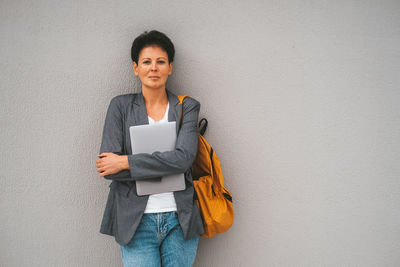 Young woman standing against wall