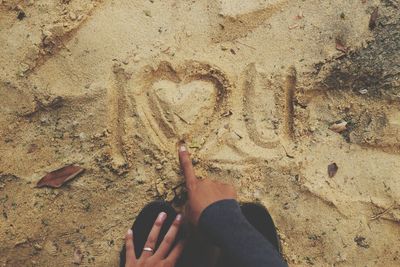 High angle view of hands on sand at beach