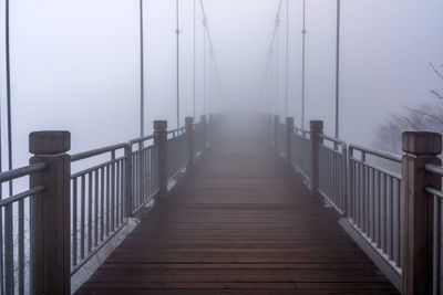 Empty wooden footbridge against sky