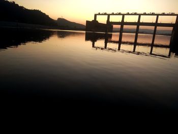 Silhouette pier on lake against sky during sunset