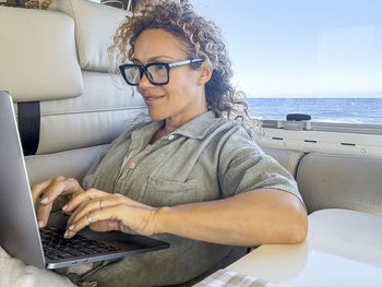 Portrait of young man using mobile phone while sitting on boat in sea