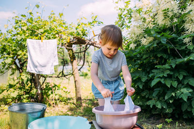 Little preschool girl helps with laundry. child washes clothes in garden