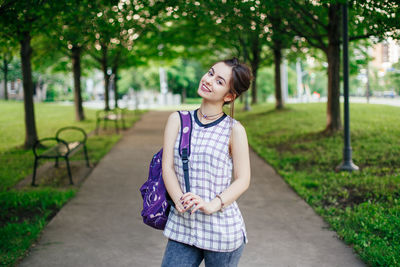 Portrait of smiling young woman standing in park