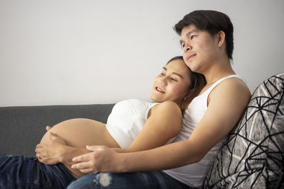 Mother and daughter sitting on wall at home