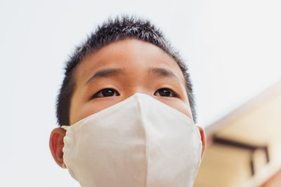 Close-up of boy wearing mask against clear sky