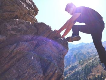 Low angle view of man standing on cliff against sky