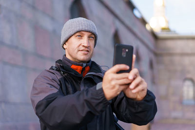 Portrait of an adult man in a gray hat and jacket on the background of the wall person