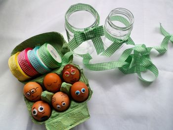 High angle view of eggs decorated on crate with ribbons and jars