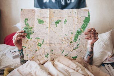 Woman holding world map while lying on bed at home