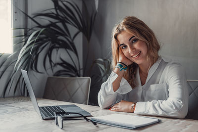 Portrait of young woman using mobile phone at office