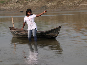 Side view of woman standing in boat in lake