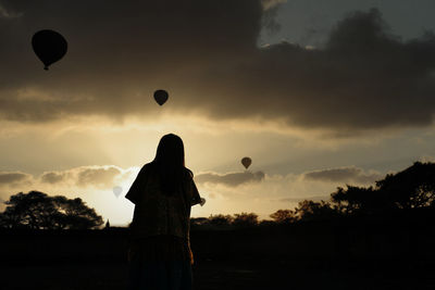 Silhouette man standing on hot air balloon against sky during sunset