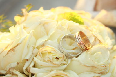 Close-up of wedding rings on yellow rose bouquet