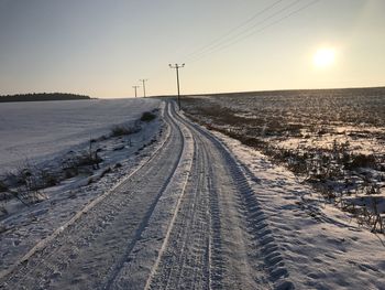 Snow covered landscape against sky during sunset