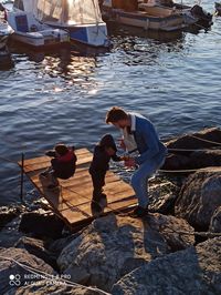 People sitting on rock by lake