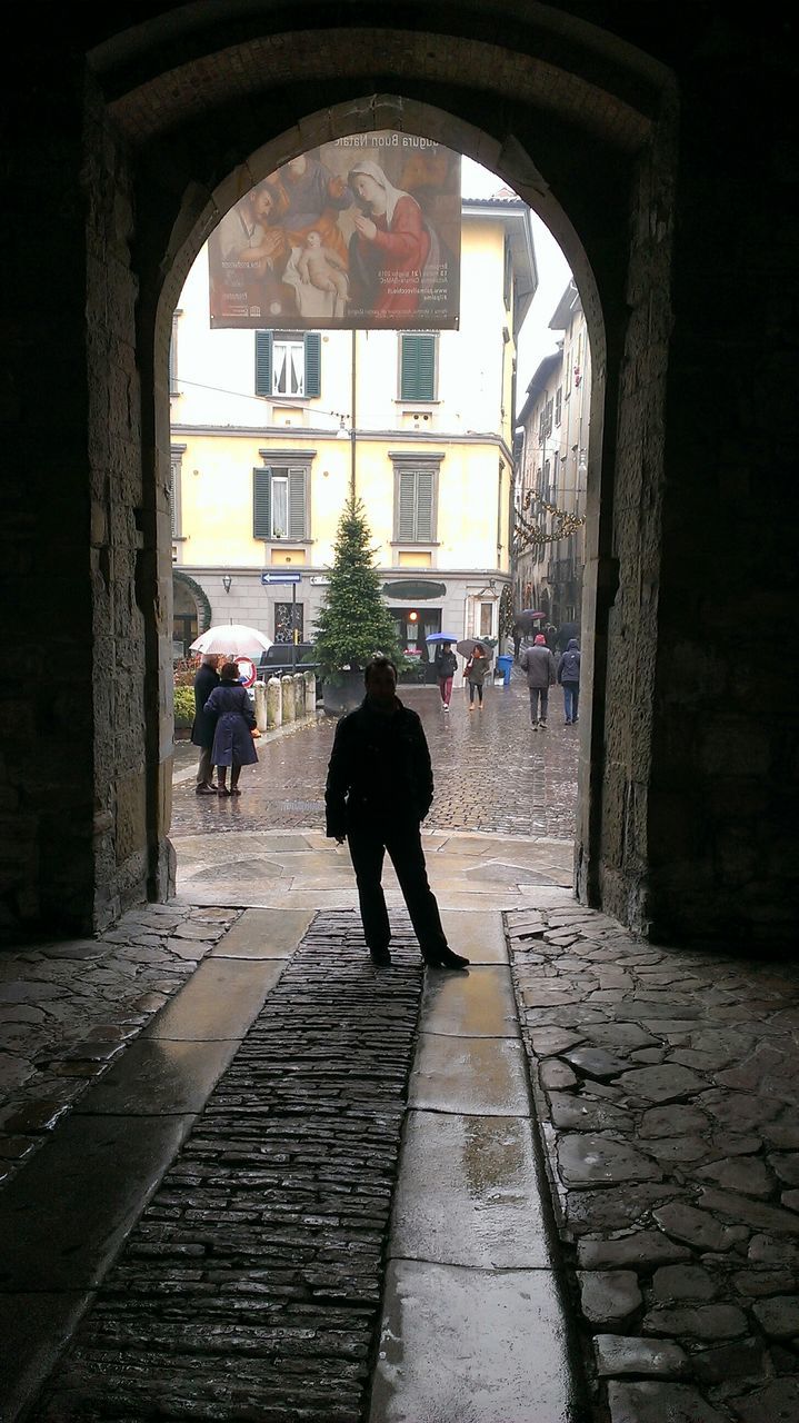 architecture, built structure, building exterior, walking, arch, men, street, full length, person, cobblestone, lifestyles, city, rear view, building, the way forward, city life, leisure activity, day, incidental people