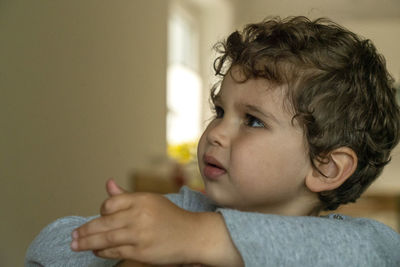 Close-up portrait of cute boy looking away at home