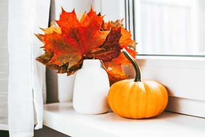 Autumn home decoration on the window using dry leaves and pumpkin