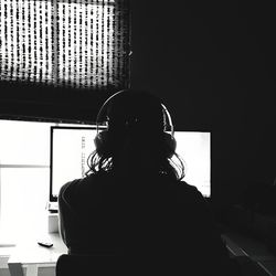 Rear view of woman sitting at window