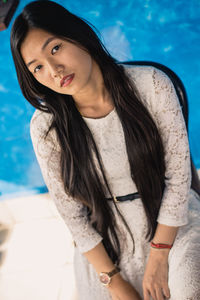 High angle portrait of beautiful young woman sitting against wall