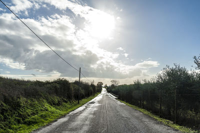 Road amidst trees against sky