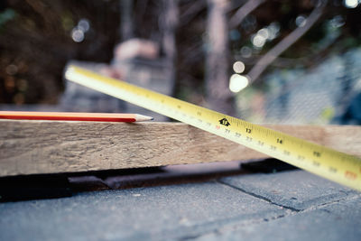 Close-up of tape measure by pencil on wood in workshop