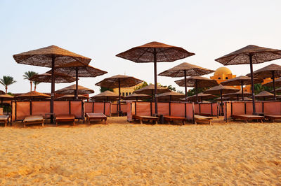 Lounge chairs and parasols on beach against clear sky