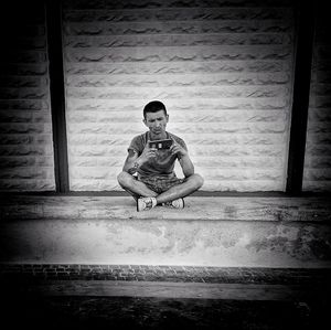 Young man sitting on window