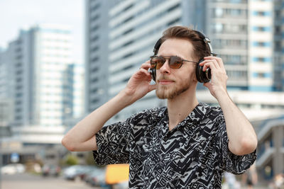 Young man wearing sunglasses while standing in city