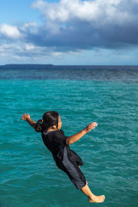 Full length of girl jumping in sea against sky